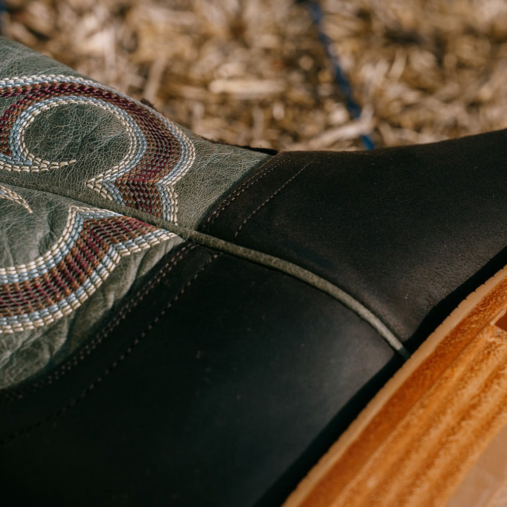 Detail shot of seam of brown and blue cowboy boot with blue, white and brown intricate stitching
