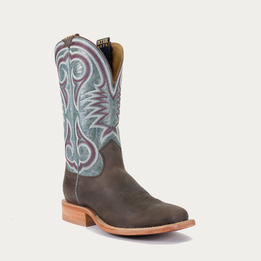A brown and blue smooth leather cowboy boot with intricate white and red stitching patterns on the shaft