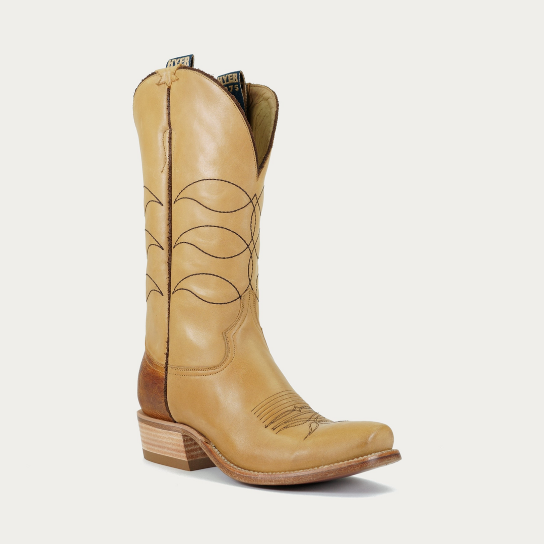 A tan leather cowboy boot with brown stitching and a wooden heel.